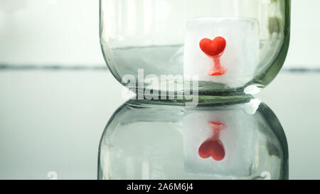 Red elastic rubber heart frozen in an ice cube melting in the sun Stock Photo