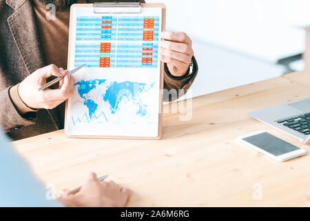 Young businessman holding clipboard with financial paper and pointing at chart Stock Photo
