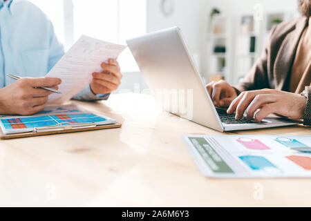 Contemporary male analysts working with electronic and paper financial documents Stock Photo