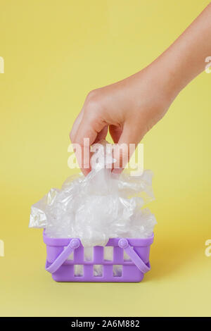polythene bags in hand in shopping basket on yellow background. Stock Photo