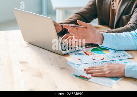 One of young analysts pointing at laptop display while working over presentation Stock Photo