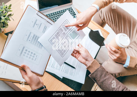 Two young creative designers of software discussing new interfaces of smartphone Stock Photo