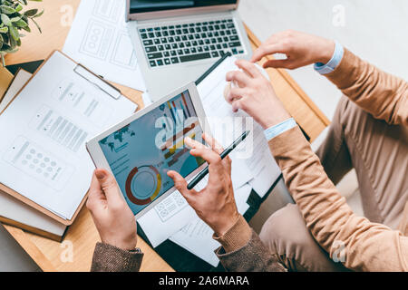Two young analysts sitting by workplace while working with data and documents Stock Photo