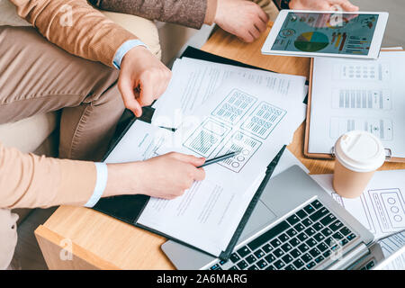 Young software or program developer with pen pointing at one of papers Stock Photo