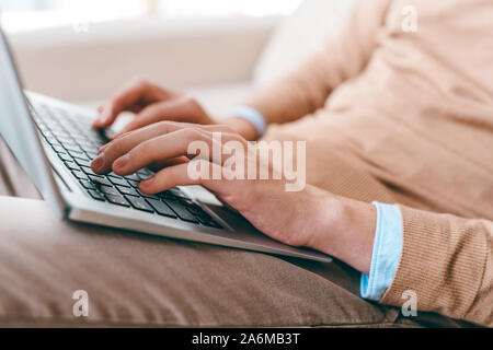 Hands of young casual man touching keys of laptop keypad while networking Stock Photo