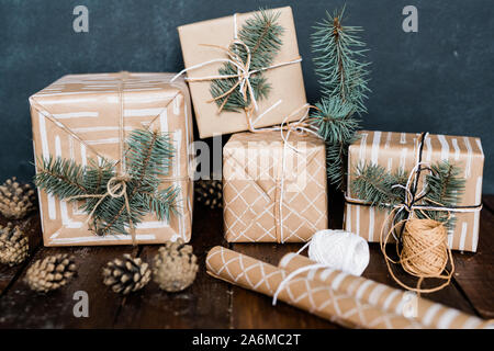 Giftboxes with conifer on top, rolled paper, threads for binding and pinecones Stock Photo