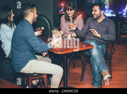 Happy friends drinking cocktails inside jazz cocktail bar - Millennial young people having fun and laughing together in british pub Stock Photo