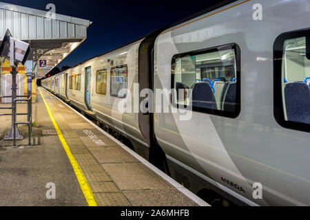 A ThamesLink train stopped at a deserted London suburban station platform at night. Stock Photo