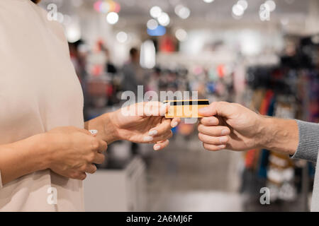 Hand of young female taking plastic card from man hand in the mall Stock Photo