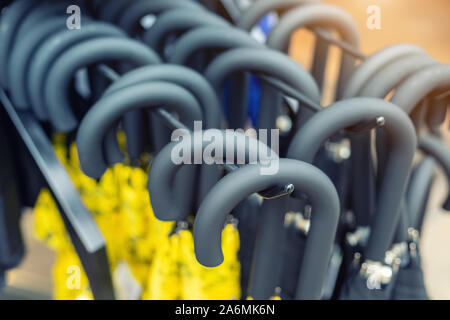 Many black handles of closed umbrellas hanged on rack for sale at shop or market Stock Photo