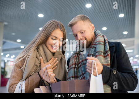 Blonde female and young man looking at purchase in one of paperbags Stock Photo