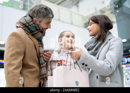 Happy young parents looking at their daughter while mother showing new purchase Stock Photo