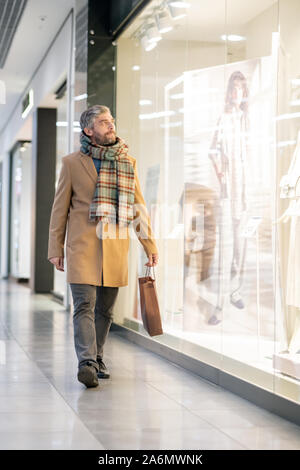 Middle aged man in stylish casualwear looking at one of large shop windows Stock Photo