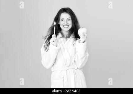 Dental care. Oral hygiene. Woman bathrobe hold toothbrush and apple. Personal hygiene. Girl cleaning teeth. Freshness and cleanliness. Keep teeth healthy. Healthy habits. Brush teeth every morning. Stock Photo