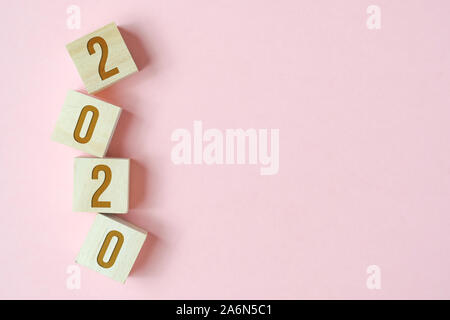 Wooden cubes with numbers symbolizing the new year 2020 on pink background with copy space. Stock Photo