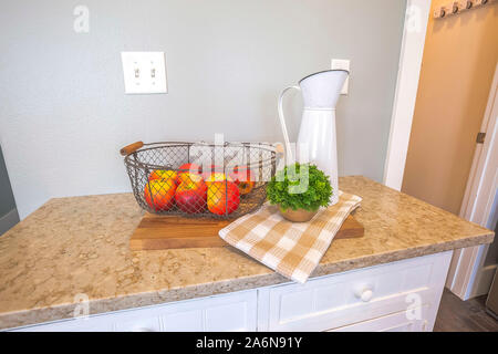 Wood cutting board with fruit basket plaid cloth potted plant and pitcher on top Stock Photo