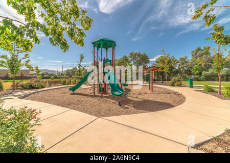 Green slides at a neighborhood playground surrounded by trees on a sunny day Stock Photo