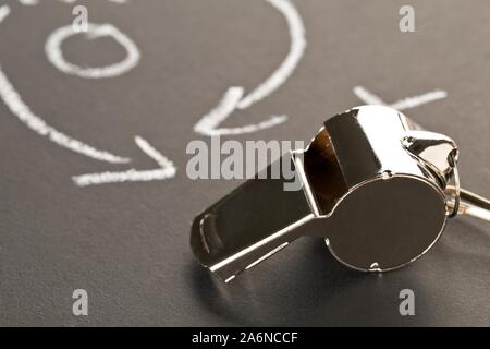 Soccer sports referee chrome whistle on blackboard background with game strategy drawing - selective focus