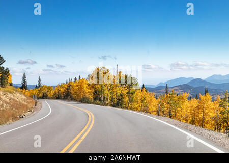 Empty highway winding through a golden fall aspen forest in a Colorado mountain landscape scene Stock Photo