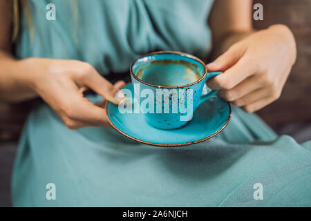 Young woman having a mediterranean breakfast seated at sofa and drinks hot aromatic coffee Stock Photo