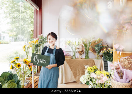 Portrait of young pretty Vietnamese woman opening her first flower shop Stock Photo