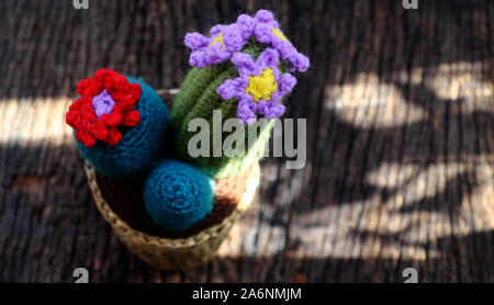 Beautiful handmade product for decorate, cacti and cactus flower crochet from green yarn, ornament plant pot on outdoor table in morning sunlight Stock Photo