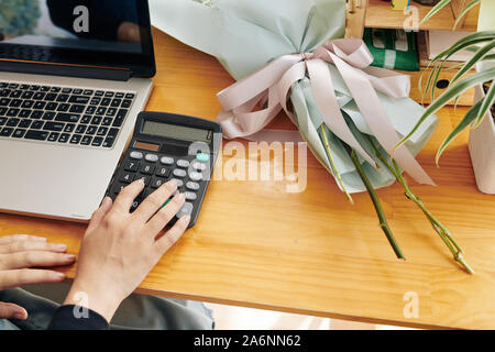 Florist using calculator when counting price of beautiful bouquet for customer Stock Photo