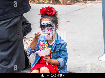 Young girl in costume enjoying ice cream at Dia de los Muertos festival, day of the dead, in San Pedro, California Stock Photo