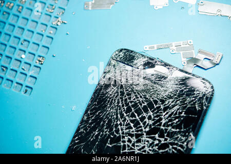 Close-up image of smashed smartphone screen on desk of repairman, view from above Stock Photo
