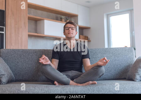 young man sitting in Lotus position on his new sofa Stock Photo