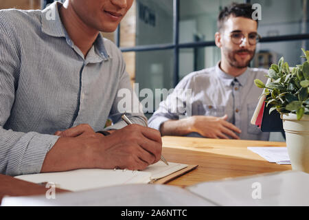 Businessman taking notes in planner when attending meeting with coworkers Stock Photo