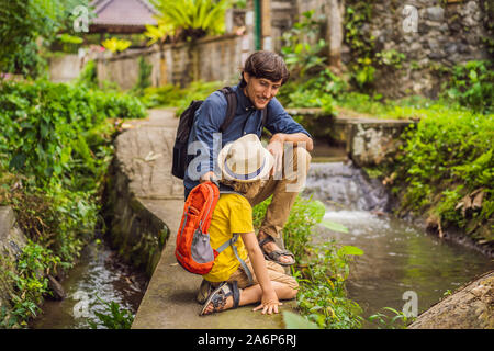 Father and son tourists in Bali walks along the narrow cozy streets of Ubud. Bali is a popular tourist destination. Travel to Bali concept. Traveling Stock Photo