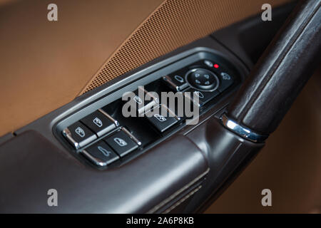 The interior of the car Porsche Cayenne Diesel 958 2012 year with a view of the dashboard, door handle and window adjust buttons with light brown leat Stock Photo