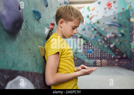 Tired or sad youngster in yellow t-shirt leaning against climbing equipment Stock Photo