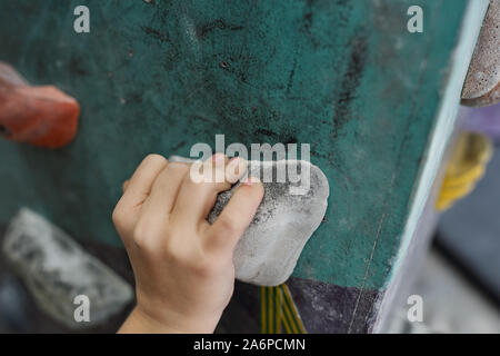 Hand of schoolboy on one of small rocks of climbing equipment Stock Photo