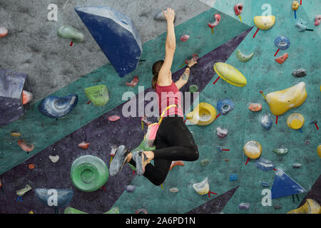 Young active woman in sportswear hanging under ceiling while holding by handles Stock Photo