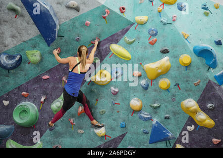 Back view of young active female hanging on climbing equipment Stock Photo