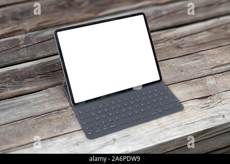 Tablet with keyboard on wooden table. Isolated screen for mockup. Stock Photo