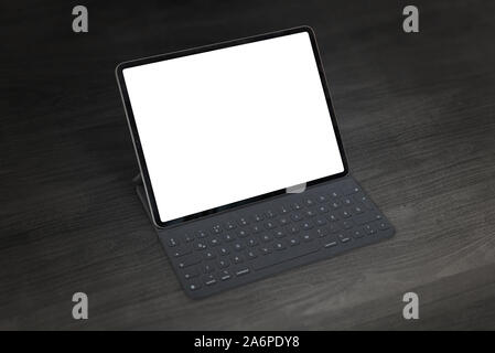 Tablet or small laptop computer mockup. Dark scene on office desk. Close-up. Isolated screen for mockup. Stock Photo