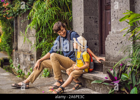 Father and son tourists in Bali walks along the narrow cozy streets of Ubud. Bali is a popular tourist destination. Travel to Bali concept. Traveling Stock Photo