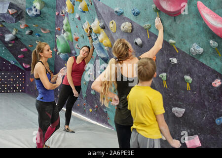 Group of active women and youthful boy having break after climbing practice Stock Photo