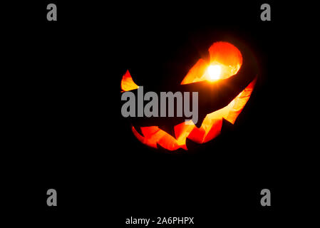 Halloween pumpkin smile and scary eyes for party night. Close up view of scary Halloween pumpkin with eyes glowing inside at black background. Selecti Stock Photo