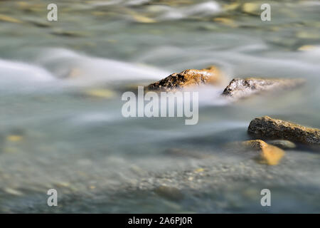 Alpine mountain river with wild water currents and beautiful natural rocks. Long exposure photography, capturing motion. Outdoor activities concept.