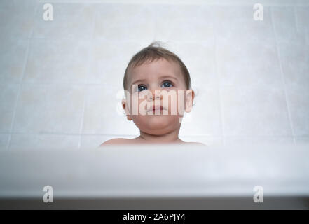 1 year old female baby sits in a high chair waiting for her meal Stock Photo