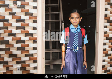 A young girl ready with uniform - small kid leaving home for school - Concept of back to school and starting kindergarten. Stock Photo