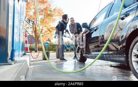 Service man helping woman cleaning her auto in car wash Stock Photo