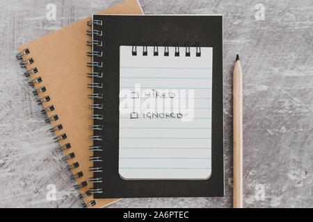 recuirment process goals conceptual still-life, notepads on business desk with Hired vs ignored options Stock Photo