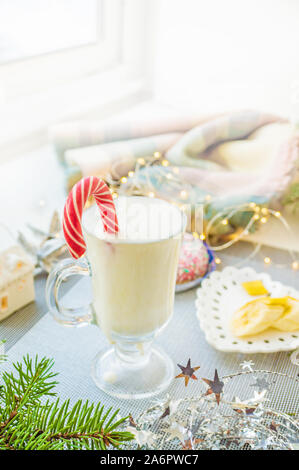 Irish traditional winter cream cocktail eggnog in a glass mug with milk, rum and cinnamon, banana covered with whipped cream, Christmas decorations. N Stock Photo