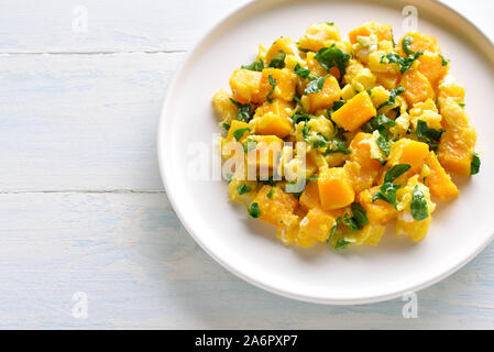 Close up of stir-fried pumpkin with eggs on plate over light wooden background. Stock Photo
