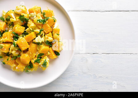 Stir-fried pumpkin with eggs on plate over white wooden background with free text space. Pumpkin and egg stir fry in thai style. Top view, flat lay Stock Photo